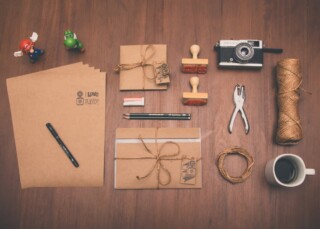 Brown papers, file, and camera lying on a wooden table